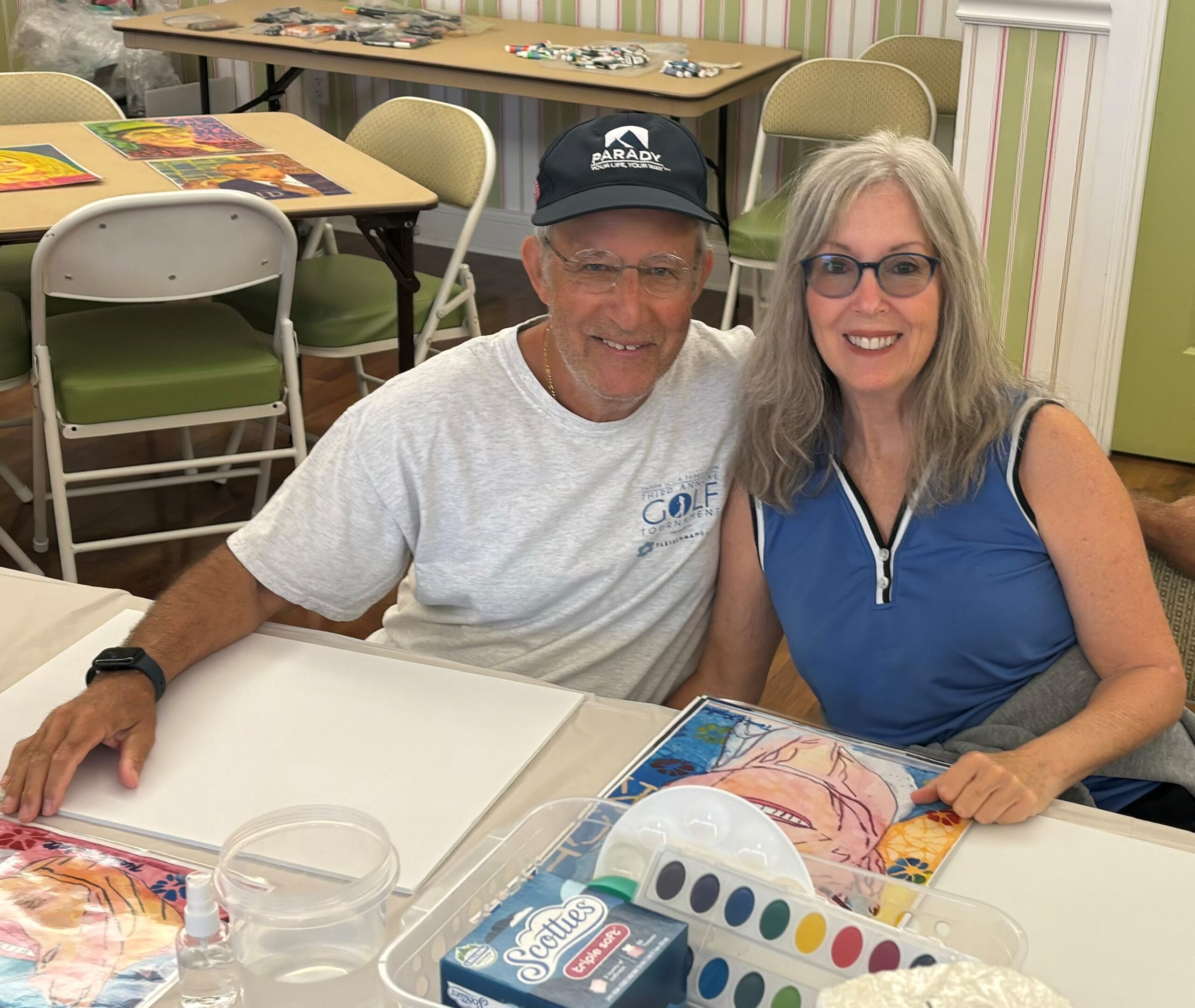 man and wife hug as they get ready to paint their portrait with instructor Neal Kimball